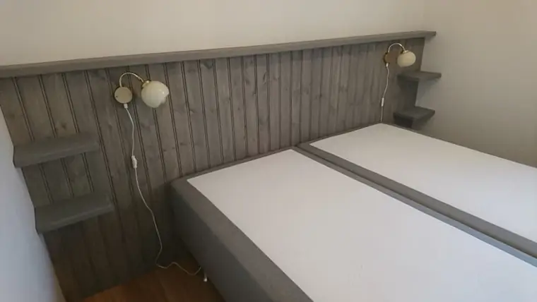 Sänggavel i trä med hyllor och belysning