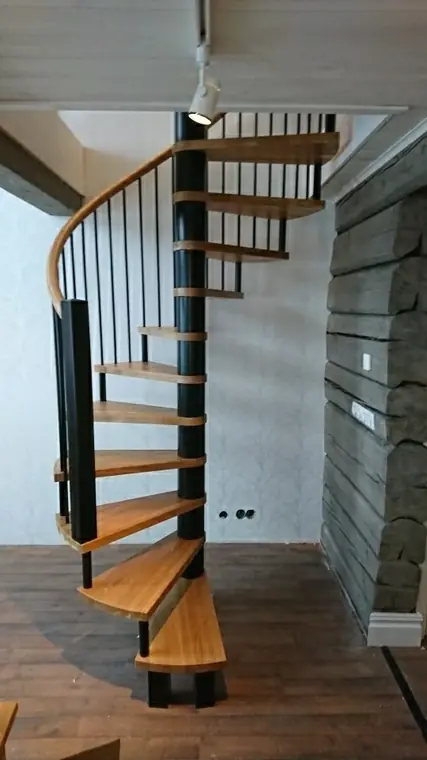 Spiraltrappa med trästeg och svart mittstolpe