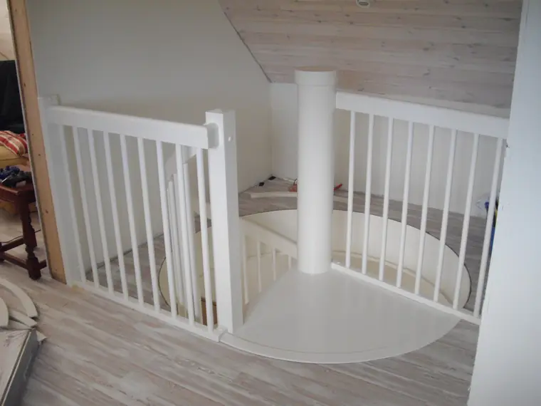 Vit svängd trappa med vita balusterstavar