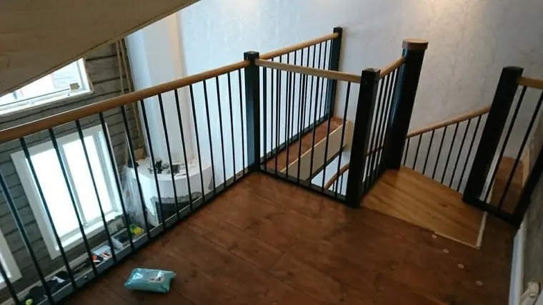 Trappavsats med svart räcke och trägolv