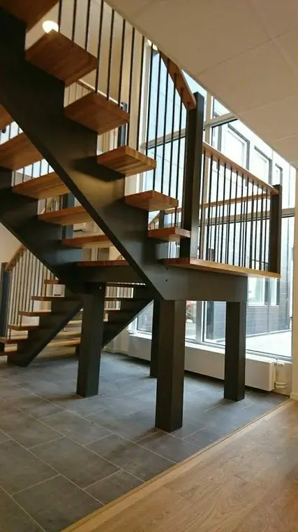 Öppen trappa med mörka vangstycken och trästeg