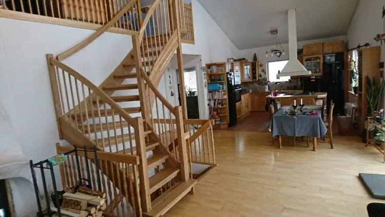 Trappa i furu med svarvade balusterstavar i öppen planlösning